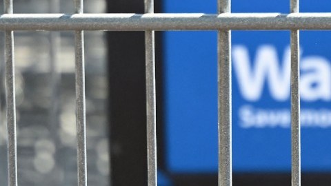 Imagen de un logotipo en color azul de la marca Walmart, en una placa de plástico en un carrito de supermercado.