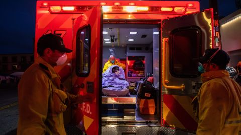 TOPSHOT - Paramedics of the LAFD Station No9 wear a face mask as a preventive measure against the spread of the COVID-19 novel coronavirus from a homeless woman who had seizures on the street at Skid Row, before boarding her in the ambulance to go to a hospital on April 12, 2020 in downtown Los Angeles, California. - One of the busiest fire station in the country , LA Fire Station 9 is on the front lines of California's homeless crisis e Coronavirus pandemic. (Photo by Apu GOMES / AFP) (Photo by APU GOMES/AFP via Getty Images)