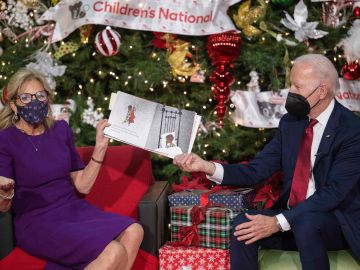 Joe Biden sostiene el libro mientras Jill Biden se lo lee a los niños.