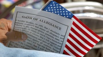 Un ciudadano estadounidense recién naturalizado sostiene el "Juramento de lealtad" y una bandera de EE.UU.