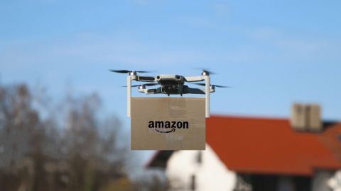 Imagen de un dron que transporta una caja de cartón con el logotipo de Amazon.