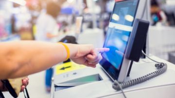 Imagen del brazo de una persona que está realizando un auto pago en una tienda.
