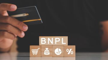 Imagen de una persona que sostiene una tarjeta de crédito y de unos cubos de madera con las letras BNPL.