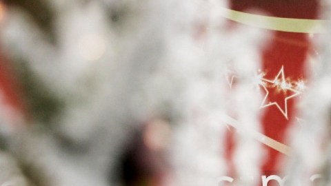 Imagen de un Santa Claus de Coca Cola impreso en un camión de color rojo y entre ramas nevadas.