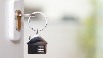 Imagen de una chapa en la que se ve un llavero con forma de una casa y una llave.