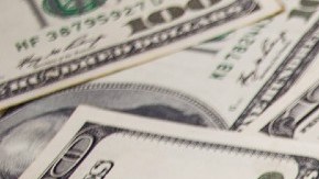 Muchos billetes de $100 dólares colocados unos sobre otros.