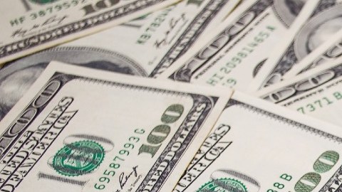 Muchos billetes de $100 dólares colocados unos sobre otros.