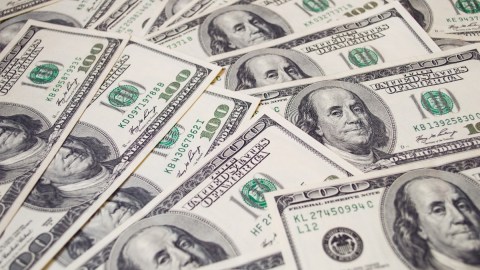 Muchos billetes de $100 dólares colocados unos sobre otros.