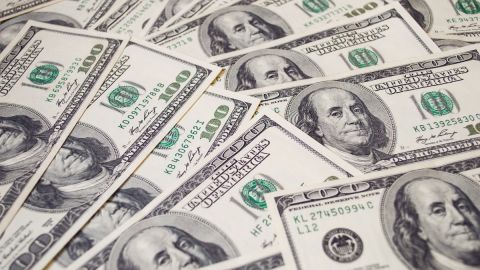 Muchos billetes de $100 dólares colocados unos sobre otros.