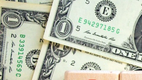 Imagen de muchos billetes y de cuatro cubos de madera que tienen los números del año 2023.