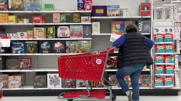 Imagen de una persona recargada en un carrito de supermercado mientras mira productos.
