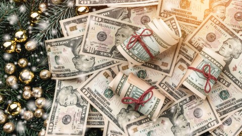 Imagen de varios rollos de billetes amarrados con lazos rojos y adornos de Navidad.