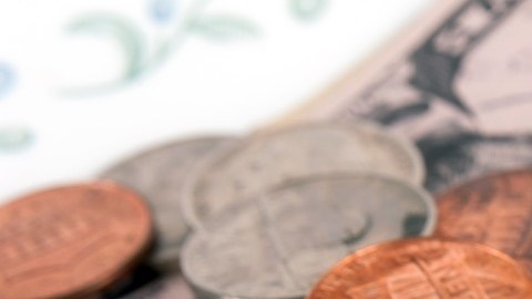 Imagen de varias monedas y un billete sobre un ticket de restaurante.