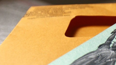 Imagen de un cheque de reembolso de impuestos de color verde y un sobre color amarillo.