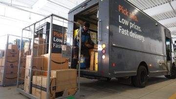 Imagen de un repartidor de Amazon mientras carga paquetes en un camión de color negro.