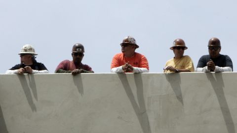 Imagen de cinco personas que están recargadas en un muro.