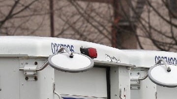 Imagen de una flota de camiones de color blanco con detalles en azul y rojo del Servicio Postal de Estados Unidos.