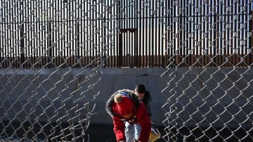 Una familia de migrantes cruza un agujero en el muro fronterizo en El Paso, Texas, el 19 de diciembre de 2022.