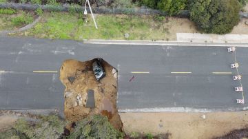 TOPSHOT - This aerial view shows two cars siting in a large sinkhole that opened during a day of relentless rain, January 10, 2023 in the Chatsworth neighborhood of Los Angeles, California. - A massive storm has arrived and is expected to cause widespread flooding throughout the state. (Photo by Robyn BECK / AFP) (Photo by ROBYN BECK/AFP via Getty Images)