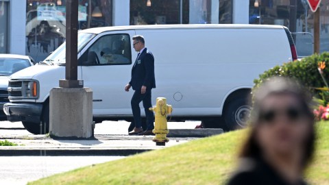 A law enforcement official walks past a body slumped over in the driver's seat of a van in Torrance, California, on January 22, 2023. - California police hunting the gunman who killed 10 people at a dance club during Lunar New Year celebrations broke into a van after a lengthy standoff, with televised footage showing the driver apparently dead. The manhunt began 12 hours earlier after a man -- described by police as Asian -- began firing at a club in Monterey Park, a city in Los Angeles County with a large Asian community. (Photo by Robyn BECK / AFP) (Photo by ROBYN BECK/AFP via Getty Images)