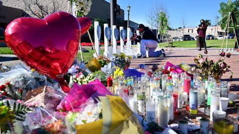 A makeshift memorial of flowers, candles and balloons grows outside City Hall in Monterey Park, California on January 24, 2023 as a man writes a note on one of 11 crosses displayed for victims of the mass shooting late on January 21. - Huu Can Tran, the 72-year-old Asian immigrant who killed 11 people before shooting himself as police moved in on him was once a regular at the California dance club where a tragic gun massacre unfolded as people celebrated the lunar new year. Tran used a semi-automatic pistol to spray 42 bullets around the Star Ballroom Dance Studio in Monterey Park, an Asian-majority city near Los Angeles. (Photo by Frederic J. BROWN / AFP) (Photo by FREDERIC J. BROWN/AFP via Getty Images)