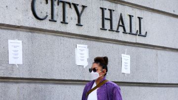 LOS ANGELES, CALIFORNIA - OCTOBER 18: A person walks past signs posted outside City Hall calling for the resignations of L.A. City Council members Kevin de Leon and Gil Cedillo in the wake of a leaked audio recording on October 18, 2022 in Los Angeles, California. L.A. City Council President Nury Martinez resigned last week in the aftermath of the release of the profanity-laced recording which revealed racist comments amid a discussion of city redistricting. (Photo by Mario Tama/Getty Images)