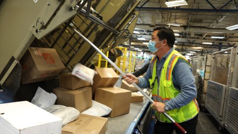 SAN FRANCISCO, CALIFORNIA - DECEMBER 14: A worker pulls packages from a bin onto a conveyor belt at the U.S. Postal Service Processing And Distribution Center on December 14, 2022 in San Francisco, California. The Postal Service is gearing up for its busiest week of the year when it is expecting to process and mail millions of cards, letters and packages. (Photo by Justin Sullivan/Getty Images)