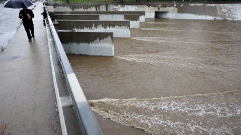 LOS ANGELES, CALIFORNIA - JANUARY 09: A person walks in the rain on a bridge crossing the Los Angeles River on January 09, 2023 in Los Angeles, California. California continues to get drenched by powerful atmospheric river events that have brought high winds and flooding rains which have toppled trees, flooded roads and cut power to tens of thousands of residents. Storms are lined up over the Pacific Ocean and are expected to bring more rain and wind through the end of the week. (Photo by Mario Tama/Getty Images)