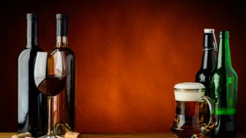 Imagen de varias botellas de vidrio de cerveza y de vino, además de una copa y un tarro.