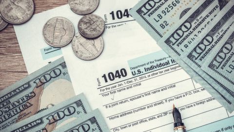 Imagen de varios formularios de impuestos, billetes y monedas.