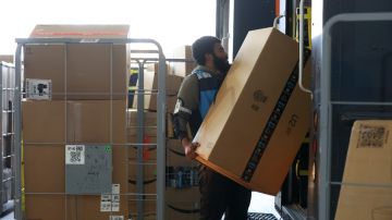 Imagen de un trabajador de Amazon que carga unas cajas a una camioneta de reparto.