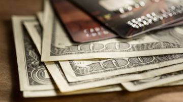 Imagen de varios billetes de $100 dólares sobre dos tarjetas de crédito.
