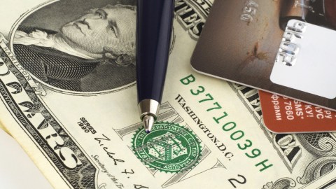 Imagen de un billete de $20 dólares, una pluma y varias tarjetas.