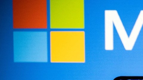 Imagen de un escenario de color azul, en el que se ve el logotipo de Microsoft y un teléfono celular con la leyenda ChatGPT.