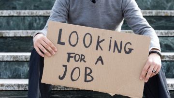 Imagen de una persona que sostiene un letrero de cartón en el que se lee una leyenda de que "busca empleo".