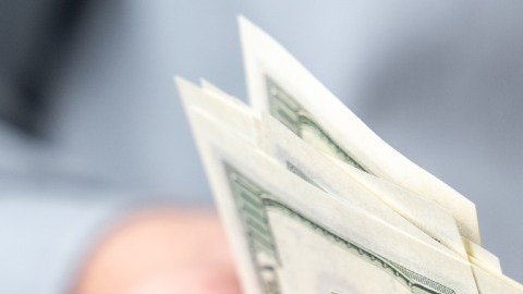 Imagen de unas manos que pasan billetes.