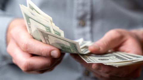 Imagen de unas manos que pasan billetes.