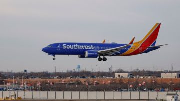 Imagen de un avión de Southwest de color azul con vivos amarillos y rojos, mientras va aterrizando.