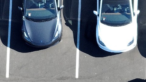 Imagen de varios vehículos de Tesla estacionados y de unas letras de color blanco con la frase Tesla.