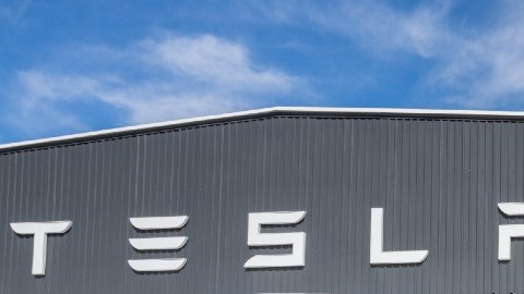 Imagen de un vehículo Tesla frente a un hangar de la misma marca.