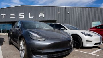 Imagen de un vehículo Tesla frente a un hangar de la misma marca.