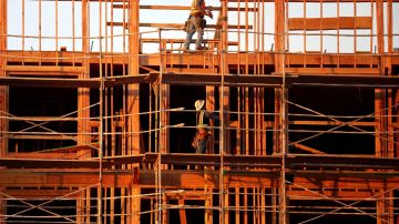 Imagen de dos personas que trabajan entre andamios en una construcción.