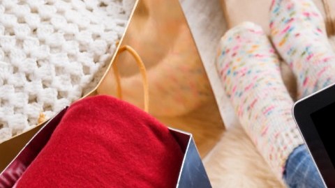 Imagen de una persona que sostiene una computadora y que está rodeada de regalos de Navidad.