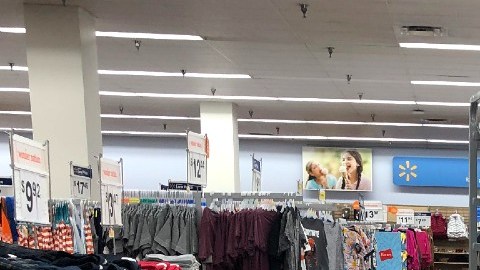 Imagen de una trabajadora de Walmart que empuja un estante en un pasillo en la tienda.