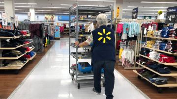 Imagen de una trabajadora de Walmart que empuja un estante en un pasillo en la tienda.
