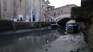 Esta fotografía tomada el 20 de febrero de 2023 muestra una góndola amarrada en el Canal Grande de Venecia, durante una fuerte marea baja en la ciudad lagunar de Venecia.