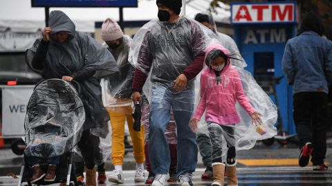 A family crosses the street in downtown Los Angeles during a winter rain storm, December 23, 2021. - Rain is expected through Christmas in the drought-stricken state. (Photo by Robyn Beck / AFP) (Photo by ROBYN BECK/AFP via Getty Images)