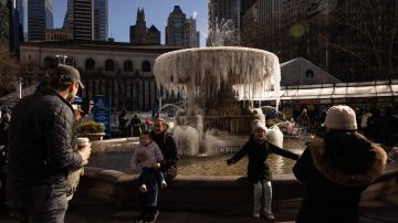 La gente toma fotos junto a una fuente congelada en Bryant Park, Nueva York.