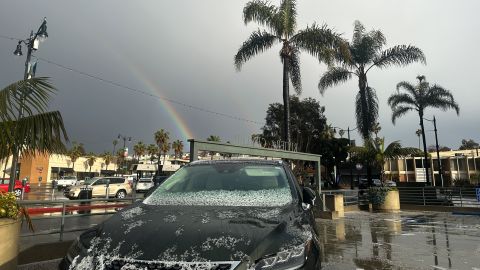 A rainbow appears between palm trees as hail partially covers a vehicle during a winter storm that blanketed the region with rain, snow, and hail in Redondo Beach, California, on February 25, 2023. - Heavy snow fell in southern California as the first blizzard in a generation pounded the hills around Los Angeles, with heavy rains threatening flooding in other places. (Photo by Patrick T. Fallon / AFP) (Photo by PATRICK T. FALLON/AFP via Getty Images)