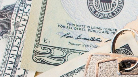Imagen de unas llaves que están colocadas sobre varios billetes.